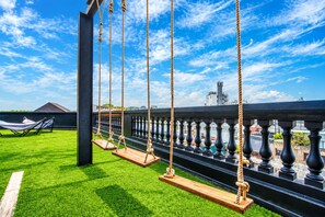 A balcony with a swing set, a hammock, and a view of a cityscape. - The Hammock Hotel Ben Thanh (Ho Chi Minh City)