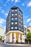 Un hotel de varios pisos con fachada oscura y numerosas ventanas.