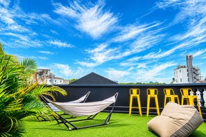 A rooftop terrace with a hammock, yellow chairs, and a green lawn. - The Hammock Hotel Ben Thanh (Ho Chi Minh City)