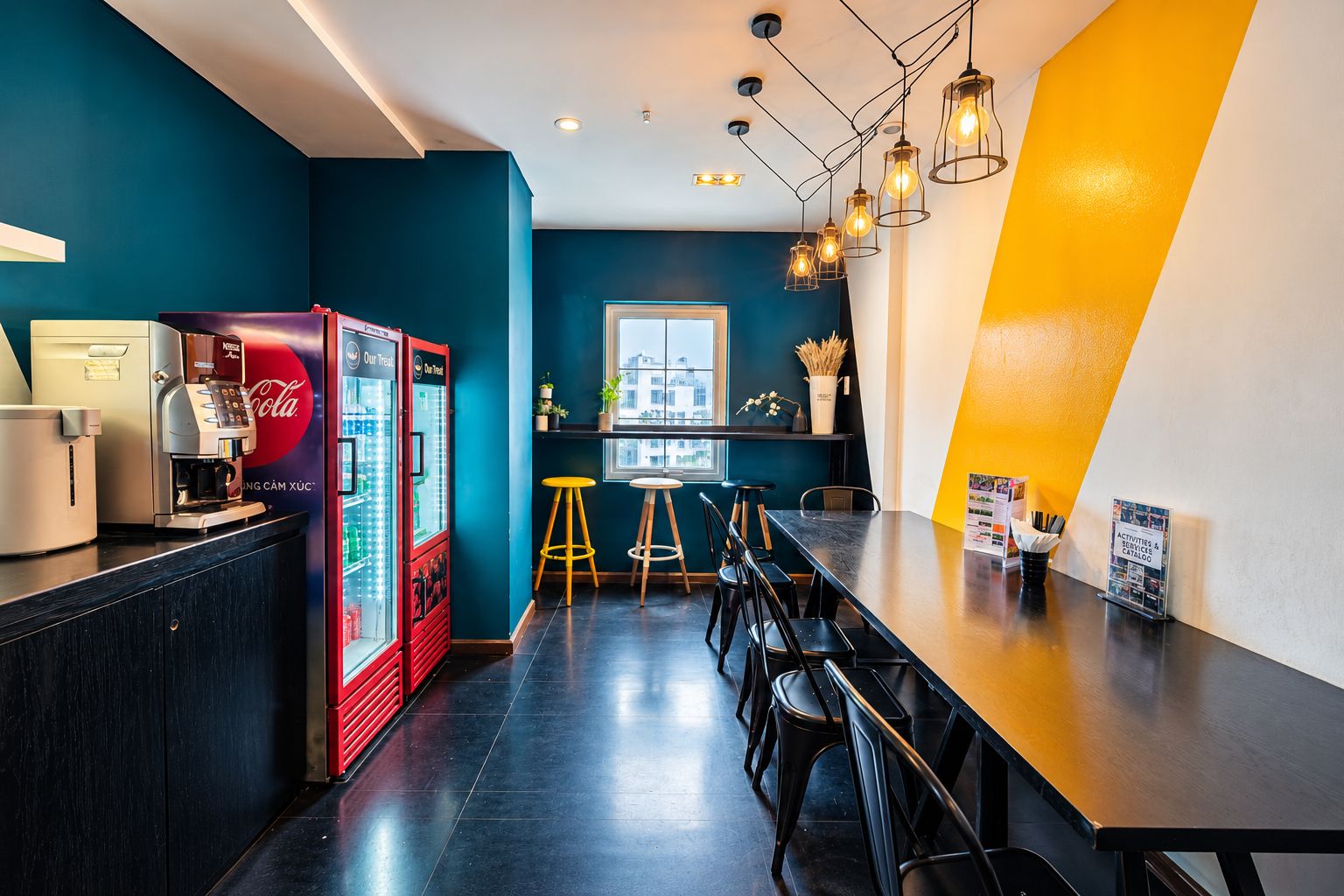 A modern bar area with a long counter, stools, and a vending machine.
