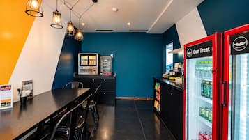 Ett modernt kafé med en svartvit färgskala, en bardisk med en meny och en röd dryckesautomat.