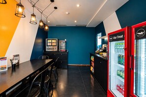 A modern cafe with a black and white color scheme, a counter with a menu, and a red beverage dispenser. - The Hammock Hotel Ben Thanh (Ho Chi Minh City)