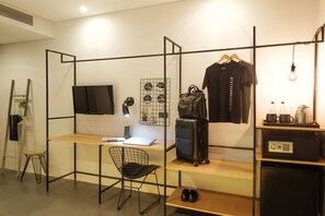 A modern hotel room with a wooden desk, a black chair, a TV, a luggage rack, and a minibar. - The Hammock Hotel Ben Thanh (Ho Chi Minh City)