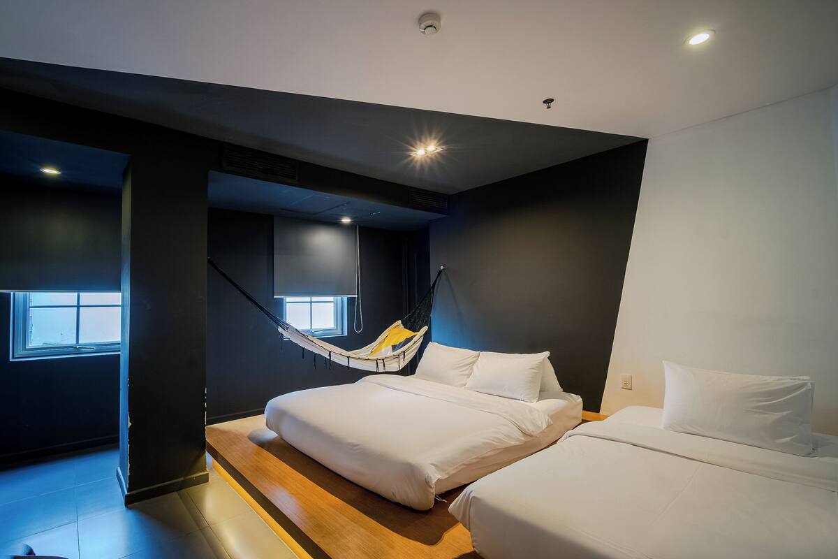 Une chambre d’hôtel moderne avec un grand lit, un hamac et une vue sur la ville.