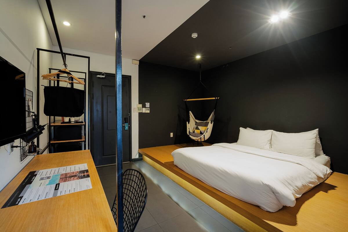 Une chambre d’hôtel moderne équipée d’un lit, d’un bureau et d’un fauteuil suspendu.