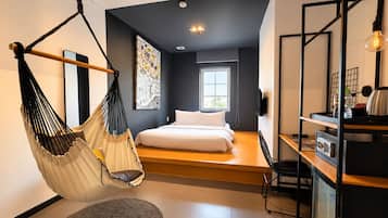 A modern bedroom with a hanging chair, a bed, a desk, and a large window.