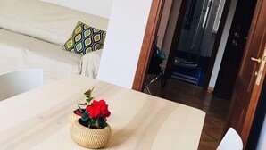 A dining area with a wooden table, a woven basket with red flowers, and a white pendant light. - Panoramic Castle Apartment, Trastevere, Old Town, Free Parking (Roma)