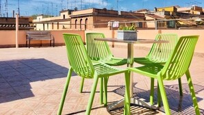 A rooftop terrace with green chairs and a table, surrounded by buildings and a clear sky. - Panoramic Castle Apartment, Trastevere, Old Town, Free Parking (Roma)
