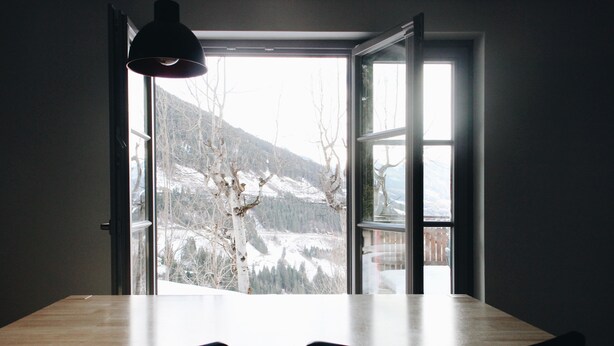 Una habitación con un ventanal grande, una mesa y dos sillas.