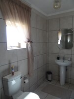 Un baño con inodoro, lavamanos y espejo.