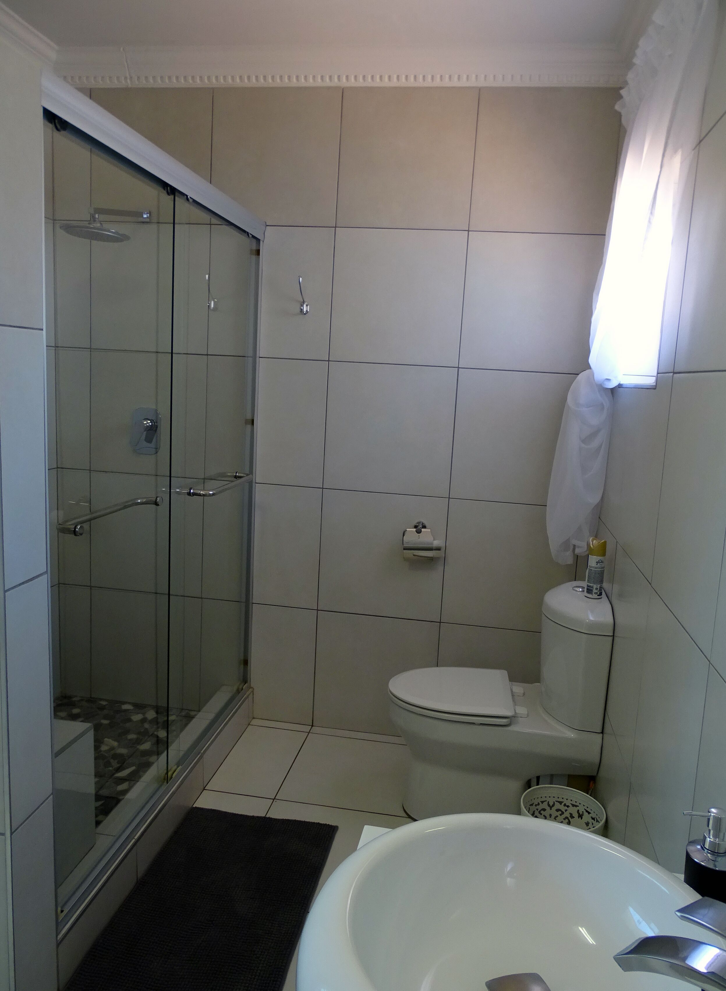 Un baño con ducha de vidrio, inodoro y lavamanos.