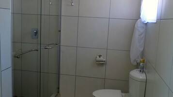 Un baño con ducha de vidrio, inodoro y lavamanos.