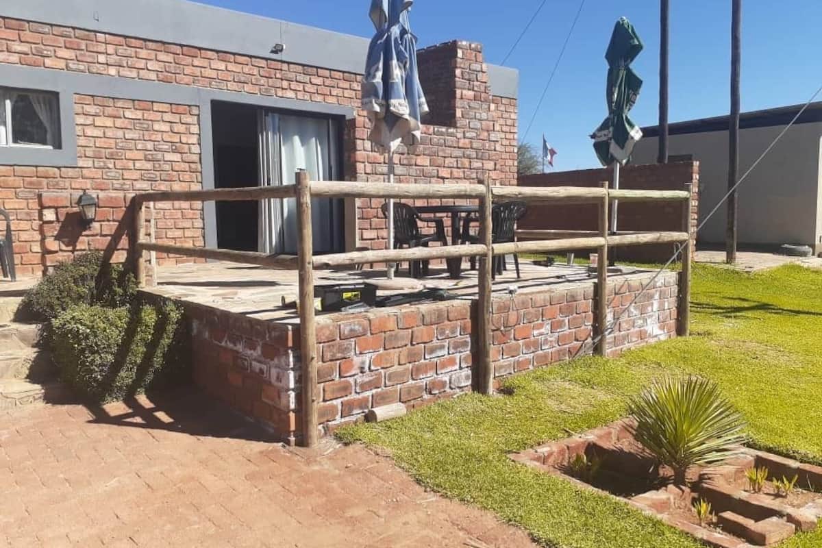 A patio area with a wooden fence, a brick wall, and a small garden.