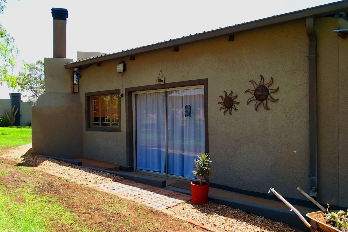 A single-story building with a flat roof, a large sliding glass door, and a small window with a decorative grille.