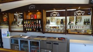 A bar area with a wooden counter, shelves of liquor bottles, and glasses. - Eden Self Catering Chalets (Windhoek)