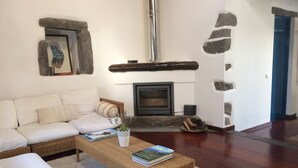 Una sala de estar acogedora con un sofá, una mesa baja con libros, una chimenea y paredes de piedra.