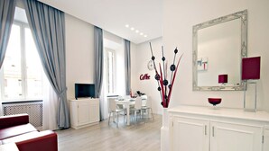 A modern living room with a TV, dining area, and a large mirror. - NEW Velvet Trastevere Apartment (Roma)