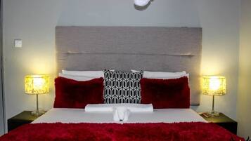 Une chambre d’hôtel avec un grand lit, deux lampes de chevet et une tête de lit.