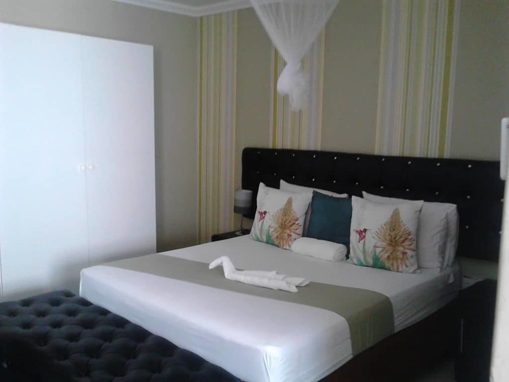 A neatly made bed with a white duvet, a black headboard, and decorative pillows.