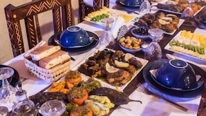A table set with various dishes, including bread, vegetables, and meats, suggesting a buffet-style meal. - Galaxy Desert Camp Merzouga (Taouz)