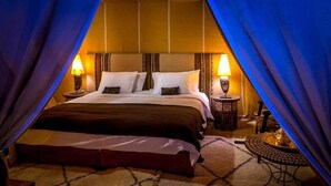 A bedroom with a large bed, two bedside tables with lamps, and a patterned rug. - Galaxy Desert Camp Merzouga (Taouz)