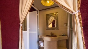 A bathroom with a vanity, a mirror, and shelves for towels. - Galaxy Desert Camp Merzouga (Taouz)
