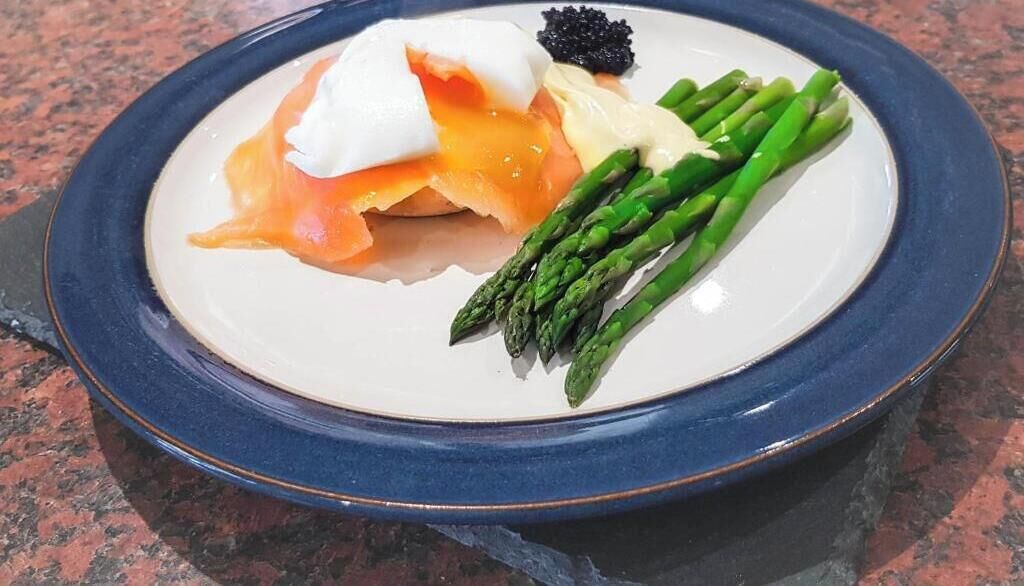Un plato con salmón ahumado, un huevo poché, espárragos y una guarnición de caviar negro.