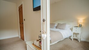 A bedroom with a bed, bedside table, lamp, and a dresser with a mirror. - Mill Lodge Brecon Beacons (Abergavenny)