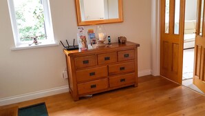 A wooden dresser with drawers, a mirror above it, and a window with a view of greenery. - Mill Lodge Brecon Beacons (Abergavenny)