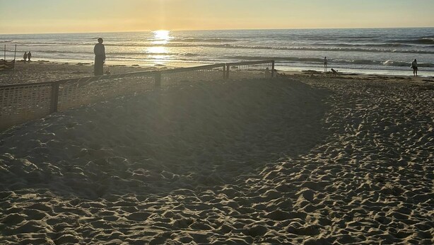 A beach with a clear sky, the sun low on the horizon, and people walking along the shore. - Vacation home for 10 pers in Westende: Rest on the Coast (Middelkerke)