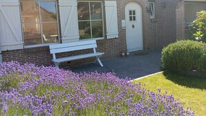A brick building with a white door, white shutters, and a bench outside. - Vacation home for 10 pers in Westende: Rest on the Coast (Middelkerke)