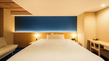 A hotel room with a large bed, a desk, a chair, and two bedside lamps.