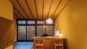 Une pièce avec un bureau en bois, deux chaises, une lampe et une grande fenêtre donnant sur un beau paysage.