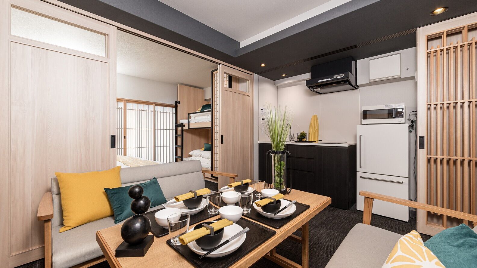 A compact living space with a dining area, kitchenette, and a sofa with cushions.