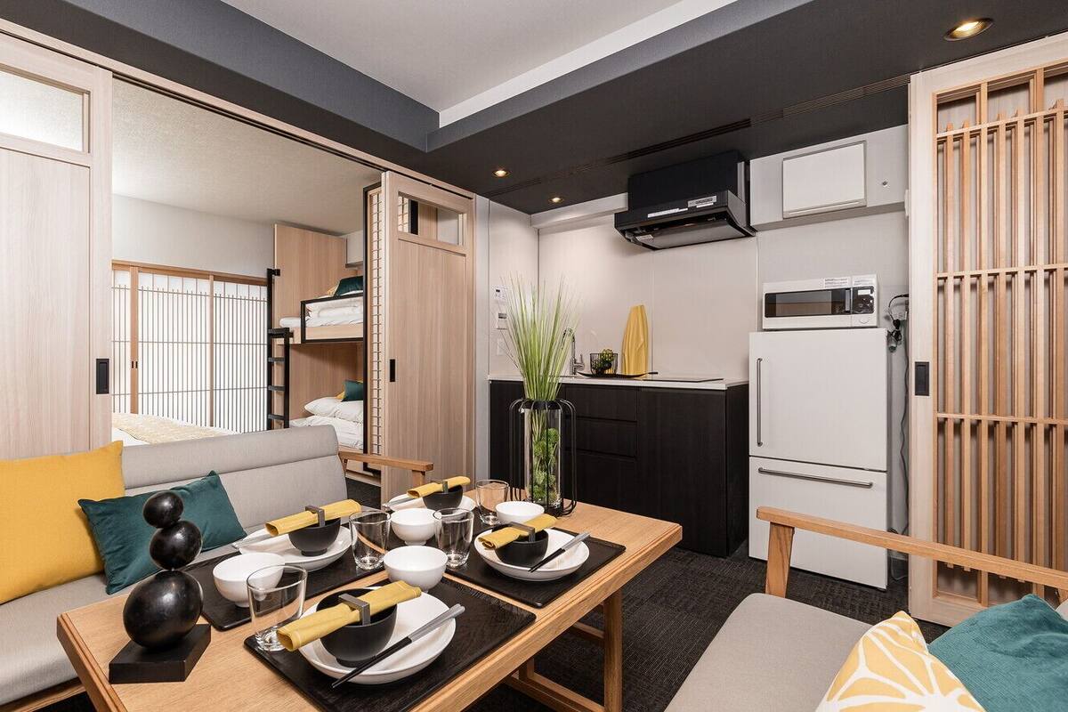 Un espace de vie compact comprenant un coin repas, une kitchenette et un canapé avec des coussins.