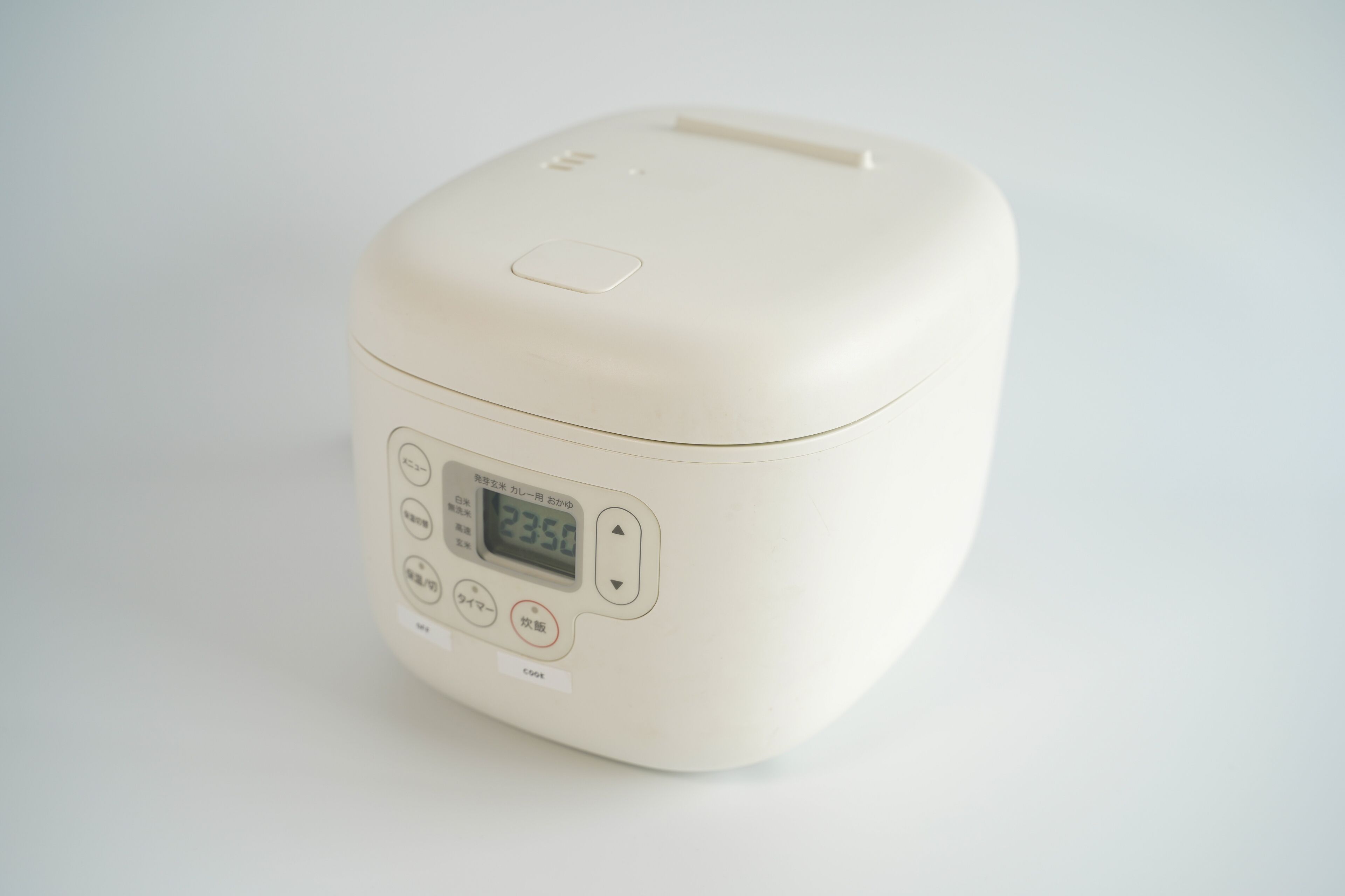 A white rice cooker with a digital display and control buttons.