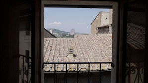 A view through a window with a tiled roof, a satellite dish, and a glimpse of a mountainous landscape. - Le Undici Lune (San Gimignano)