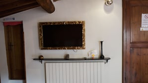 A room with a fireplace, a mounted television, and a wooden door. - Le Undici Lune (San Gimignano)