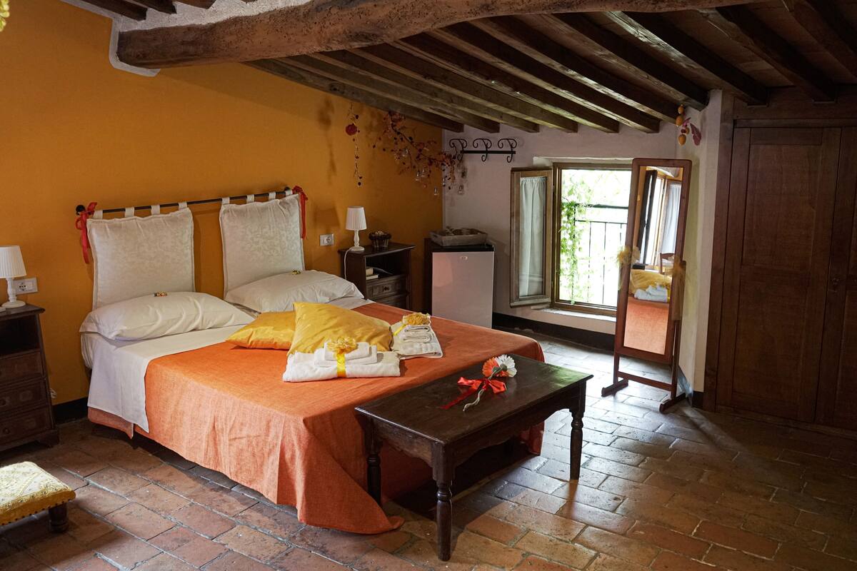 A bedroom with a bed, wooden floor, and a window with a view.