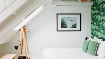 Quarto com cama, cadeira balanço, escrivaninha e quadro pendurado na parede.