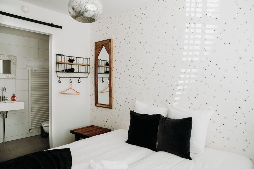 Une chambre à coucher comprenant un lit, un porte-chaussures suspendu, un miroir et un mur orné d’un motif texturé.