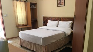 A neatly made bed with white linens, a wooden headboard, and a small shelf above it. - Laphroiag Luxury Chalets (Maun)