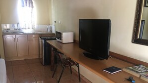 A kitchen with a microwave, a sink, and a large flat-screen TV on a wooden counter. - Laphroiag Luxury Chalets (Maun)