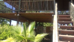 A wooden balcony with a railing, a staircase, and a palm tree in the foreground. - Laphroiag Luxury Chalets (Maun)