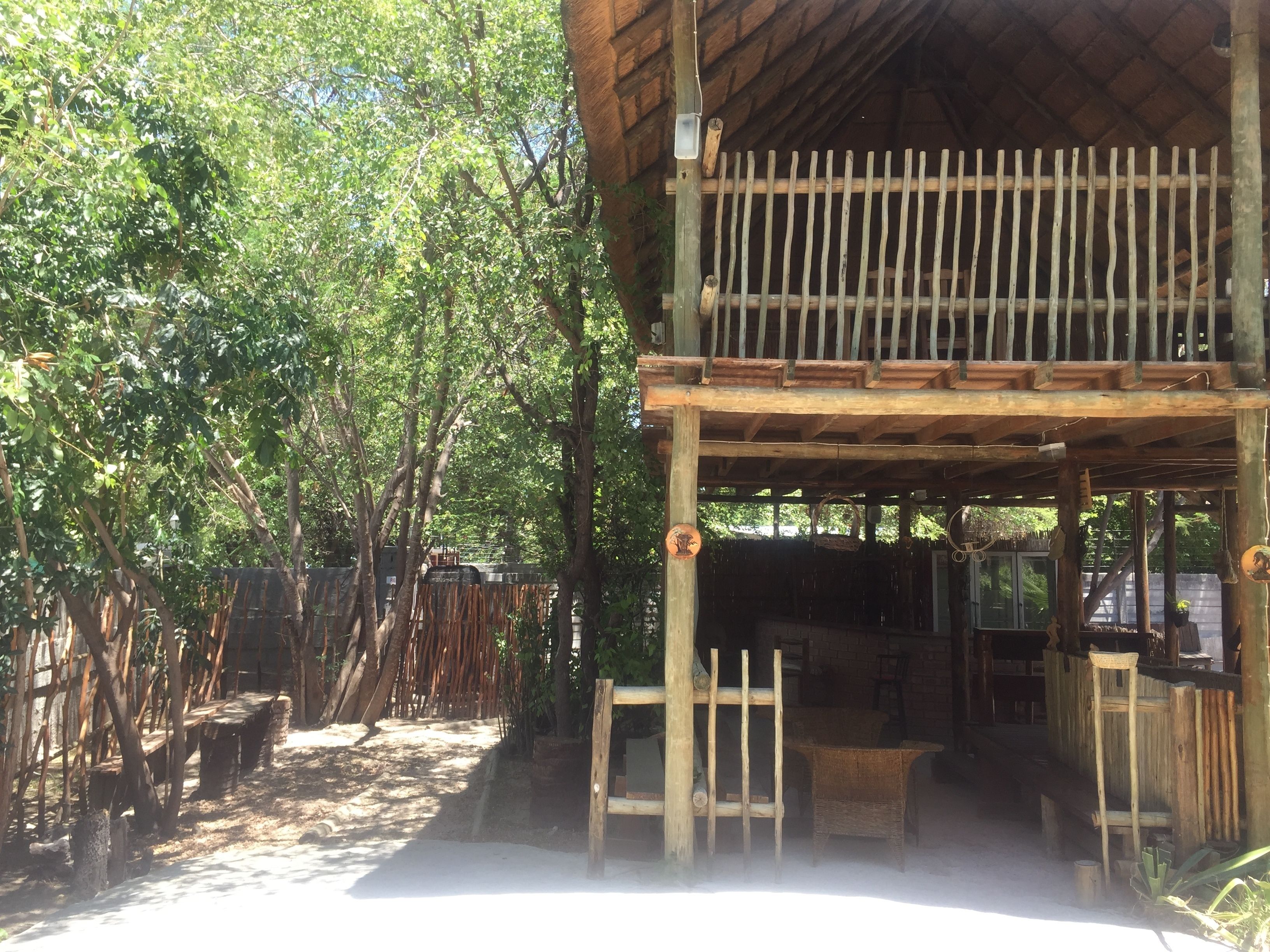 Una construcción rústica de madera con balcón, rodeada de follaje denso.