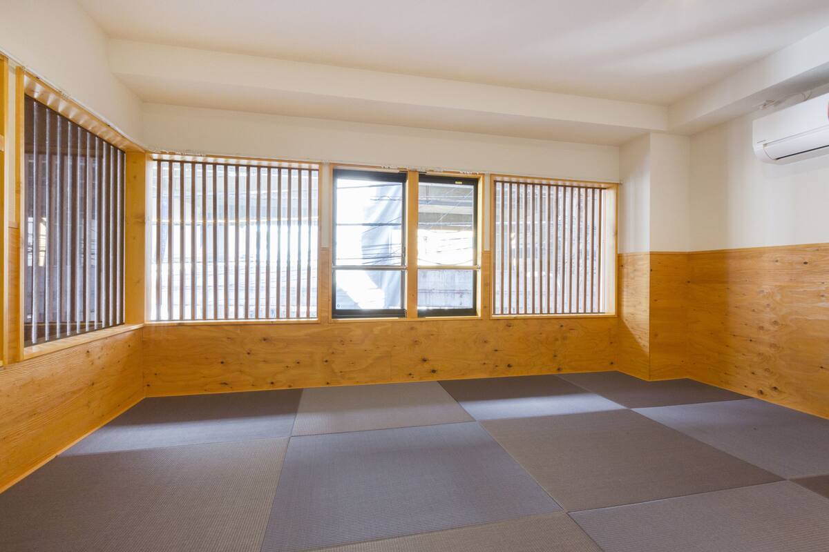 Ein Zimmer mit Tatami-Böden, Holzwänden und Shoji-Bildschirmen.