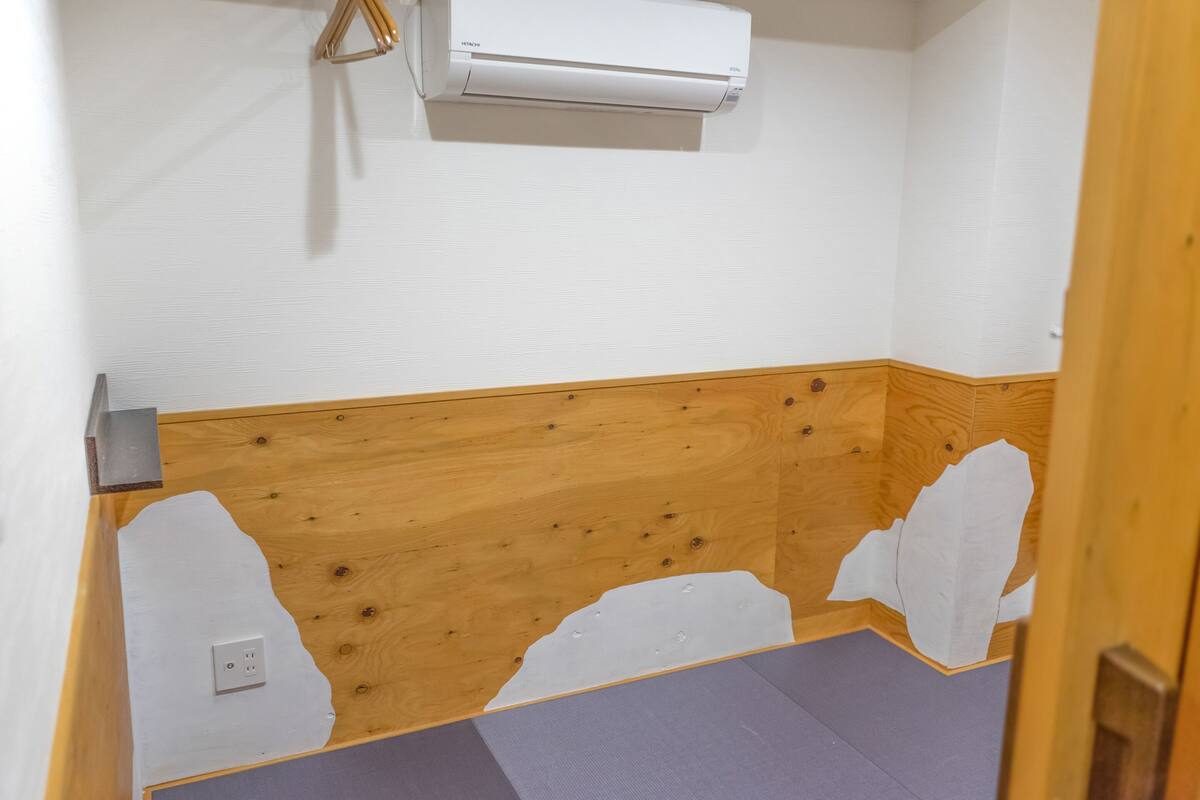 Ein Badezimmer mit Holzwänden, einer weißen Klimaanlage und einer Duschkabine.