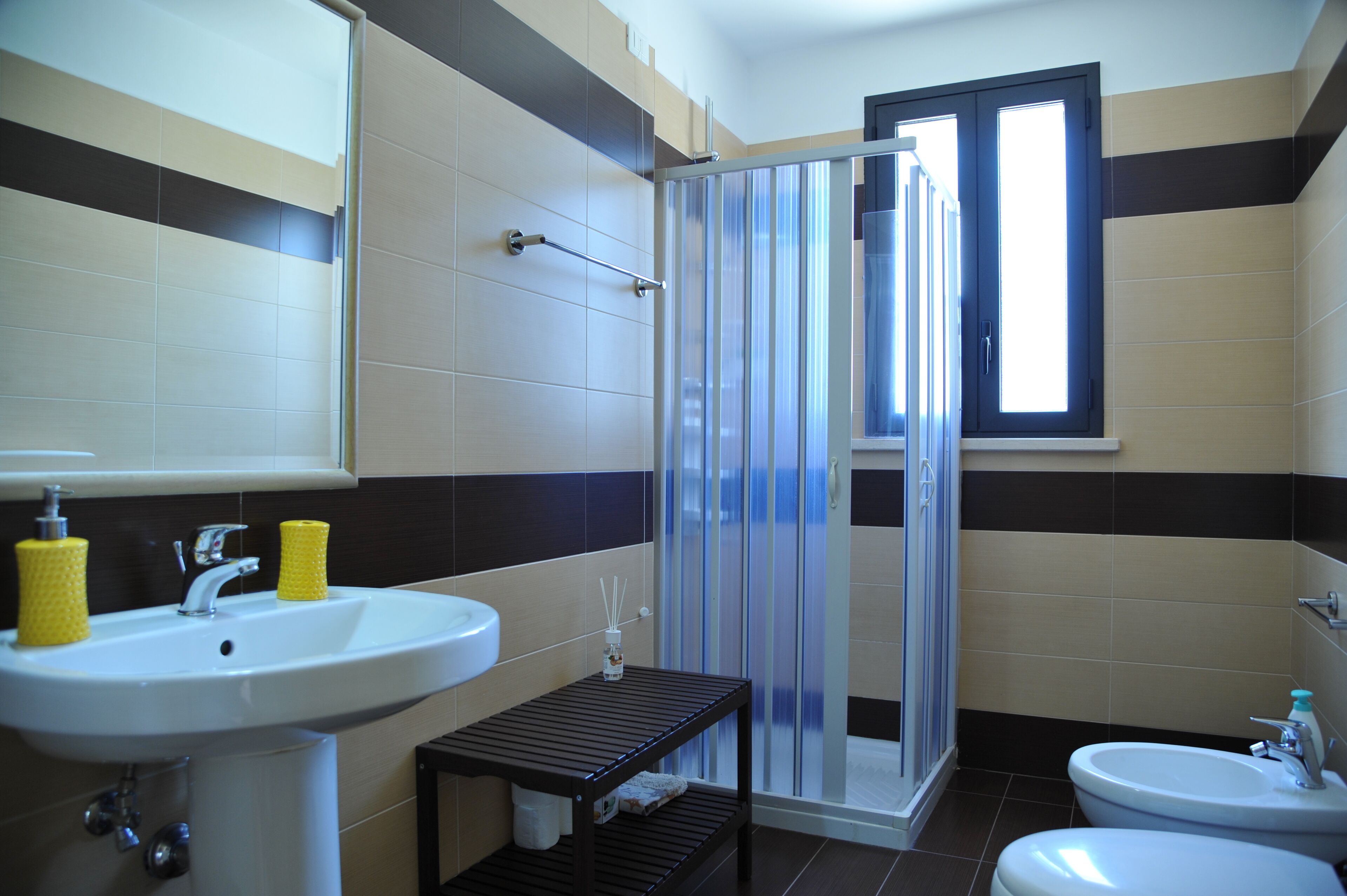 A bathroom with a shower, two sinks, and a window.