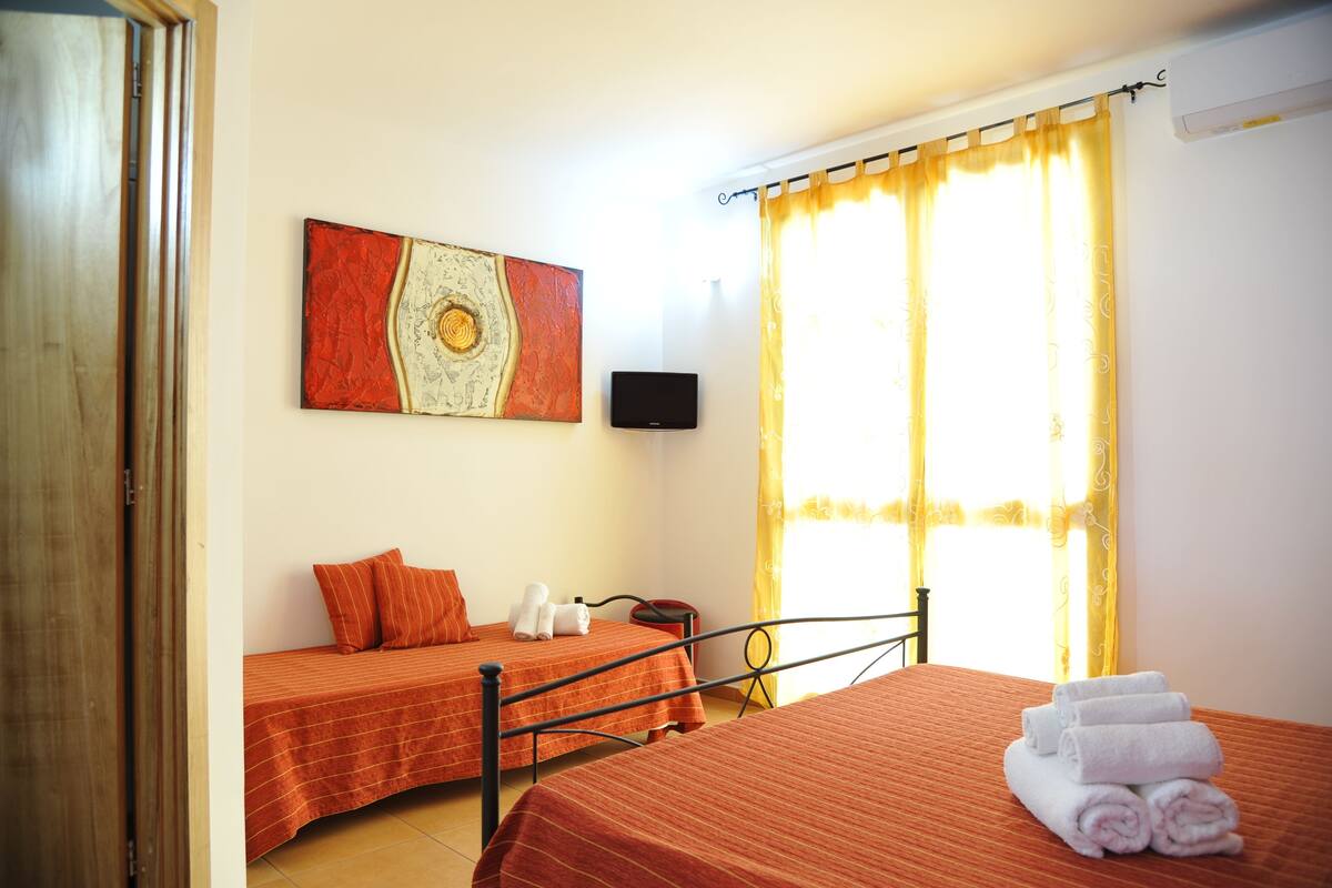 A hotel room with two beds, a TV, and a painting on the wall.