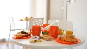 A breakfast table with orange plates, mugs, and pastries. - B&B Erminia (Presicce-Acquarica)